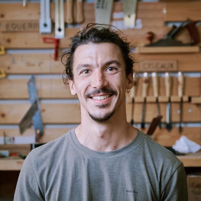 Bastien, souriant devant le tableau d'outils de l'atelier.