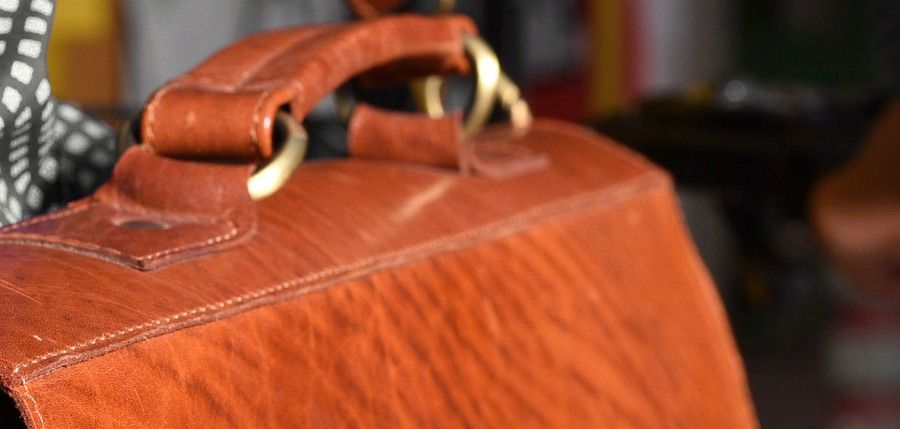 Gros plan sur le cuir fauve et les boucles de laiton d'une sacoche.