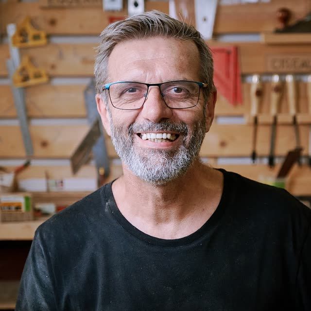 Stéphane, souriant devant le tableau d'outils de l'atelier.